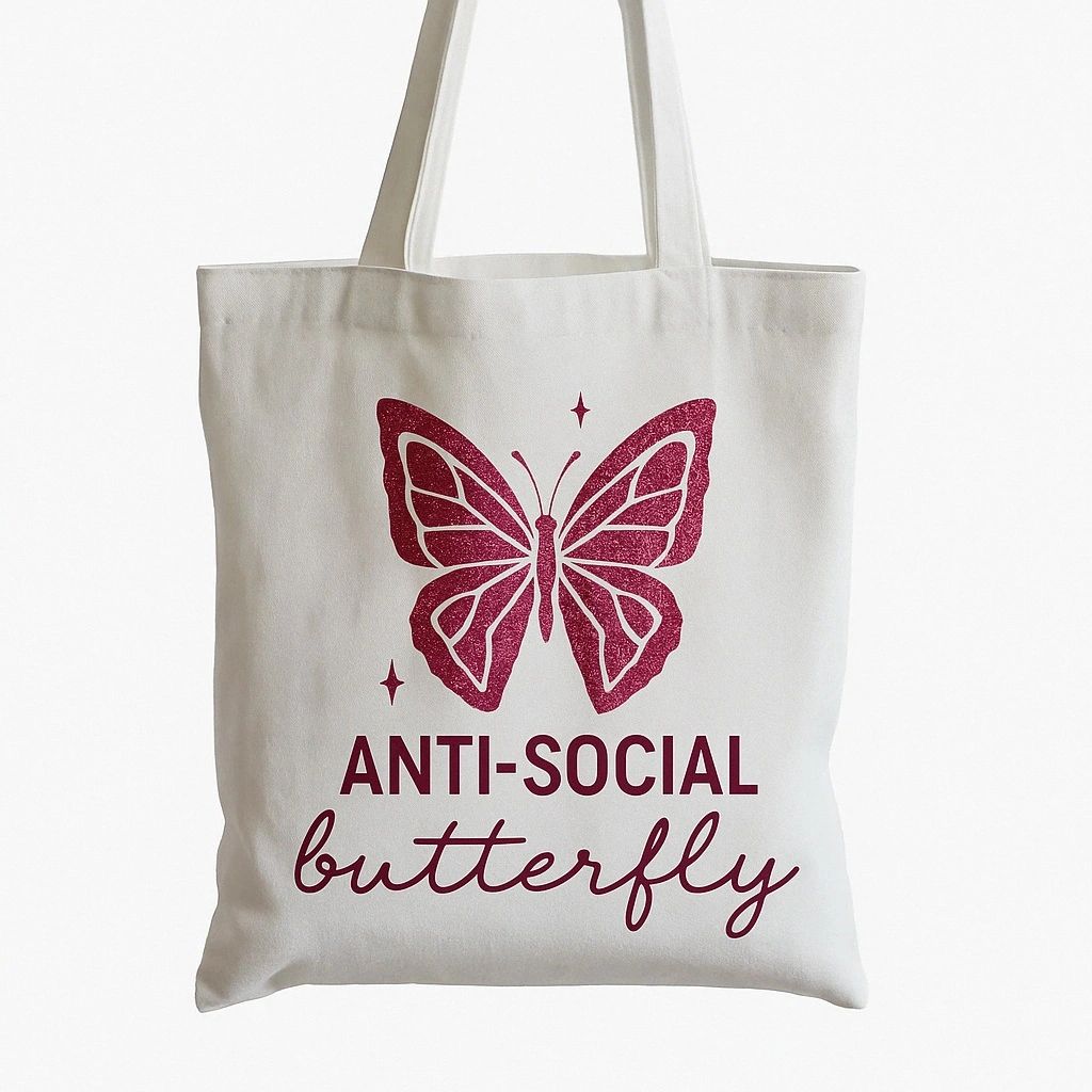 White reusable tote bag featuring a pink butterfly graphic with “Anti-Social Butterfly” text design. Funny introvert tote bag perfect for shopping, school, books, errands, casual everyday use, and aesthetic fashion lovers.