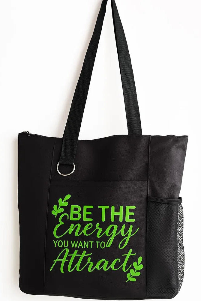 Black tote bag featuring the motivational quote “Be the Energy You Attract” in bright green typography. Stylish everyday tote with strong shoulder straps for shopping, work, school, travel, errands, books, groceries, and daily essentials. Inspirational quote bag designed for positive mindset, self-growth, mindfulness, confidence, and uplifting everyday fashion.