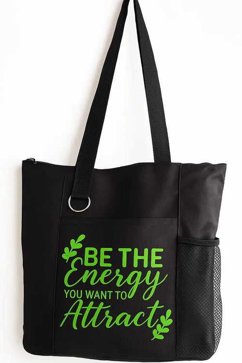 Black tote bag featuring the motivational quote “Be the Energy You Attract” in bright green typography. Stylish everyday tote with strong shoulder straps for shopping, work, school, travel, errands, books, groceries, and daily essentials. Inspirational quote bag designed for positive mindset, self-growth, mindfulness, confidence, and uplifting everyday fashion.