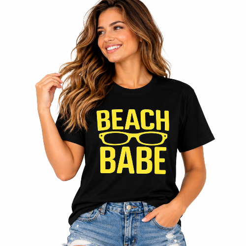 A woman wearing a black short-sleeve graphic t-shirt with 'BEACH BABE' and sunglasses printed in yellow, paired with distressed blue jeans, against a solid white background.