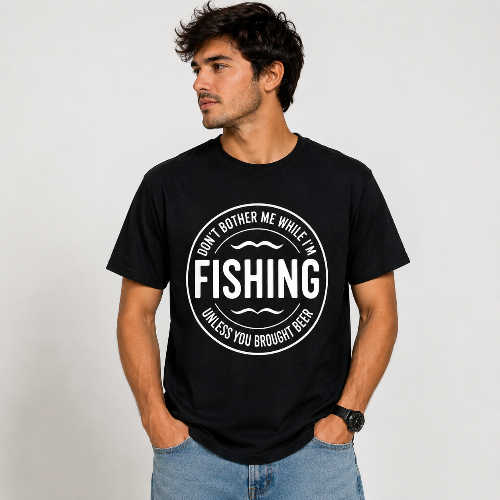 A man wearing a black crewneck t-shirt with a white circular graphic that reads 'DON'T BOTHER ME WHILE I'M FISHING UNLESS YOU BROUGHT BEER'.