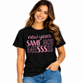 A woman wearing a black short-sleeve graphic T-shirt with pink text reading 'new year SAME HOT MESSSSS' and blue jeans, photographed against a clean white studio background.