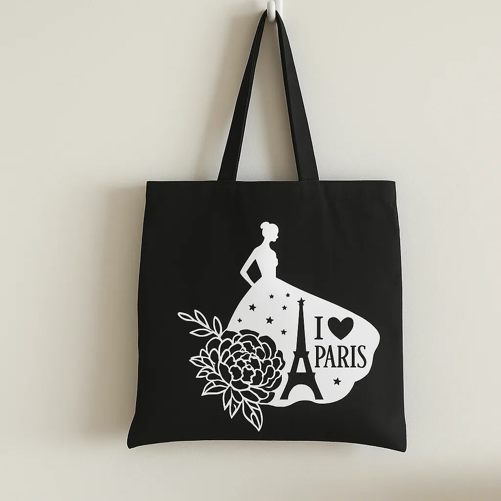 Black cotton tote bag with white Paris graphic, Eiffel Tower silhouette, and floral artwork, reusable travel shopper tote for shopping, school, vacation, books, errands, and everyday fashion use