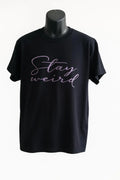 Black graphic t shirt featuring the phrase Stay Wild in stylish script lettering, designed to celebrate freedom, individuality, adventure, and self-expression.