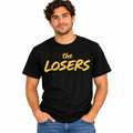 Man wearing a black The Losers graphic T-shirt with bold mustard yellow lettering.