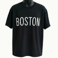 Black graphic t-shirt featuring the word "Boston" in clean white typography, stylish unisex city-inspired graphic tee for casual everyday wear.