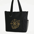 Black reusable tote bag featuring a gold compass design, travel inspired shoulder tote for shopping, books, groceries, vacations, adventures, and everyday carry