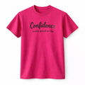 Pink unisex graphic T shirt featuring the phrase Confidence Looks Good on Me in elegant script lettering with a motivational self-confidence design.