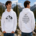 A man wearing a white pullover hoodie with black graphic text and mountain illustrations, shown in front and back views against a mountain lake background.