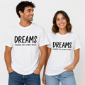 A man and a woman modeling matching white graphic t-shirts with the black printed text 'DREAMS really do come true' on the chest, paired with blue jeans against a clean white background.