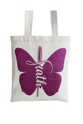 White canvas tote bag featuring a purple butterfly graphic with elegant Faith script lettering on a reusable everyday carry tote.