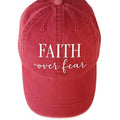 Red baseball cap featuring a white Faith Over Fear graphic design on the front with an adjustable back closure for casual everyday wear.