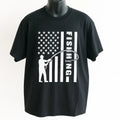 Black Fishing American Flag Graphic T Shirt featuring a fisherman casting a line across a distressed USA flag design. Patriotic fishing apparel for anglers and outdoor enthusiasts.