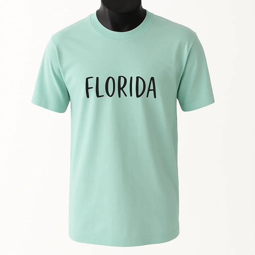 Mint green graphic t-shirt featuring the word "Florida" in bold black typography. Casual unisex travel-inspired shirt perfect for beach vacations, Florida lovers, tourists, road trips, summer outfits, and everyday wear.