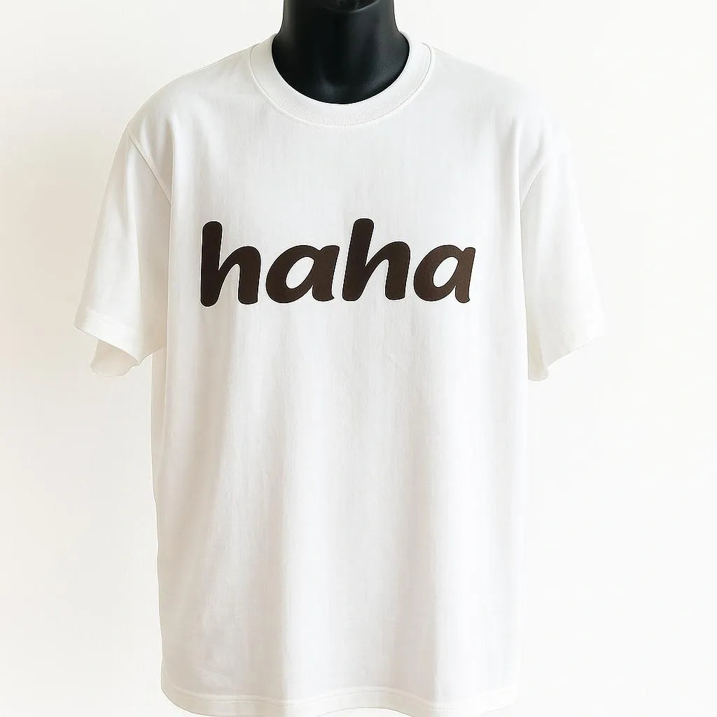 White graphic t-shirt featuring the word "haha" in bold black lettering, funny minimalist unisex graphic tee for casual everyday wear.