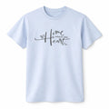 Light blue unisex graphic T shirt featuring the phrase Home Is Where the Heart Is in elegant script with a minimalist home and love inspired design.