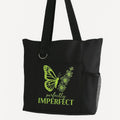 Black reusable tote bag with green butterfly graphic and imperfect inspirational typography design, shoulder tote for shopping, travel, work, school, everyday carry, self love, and motivational lifestyle accessories