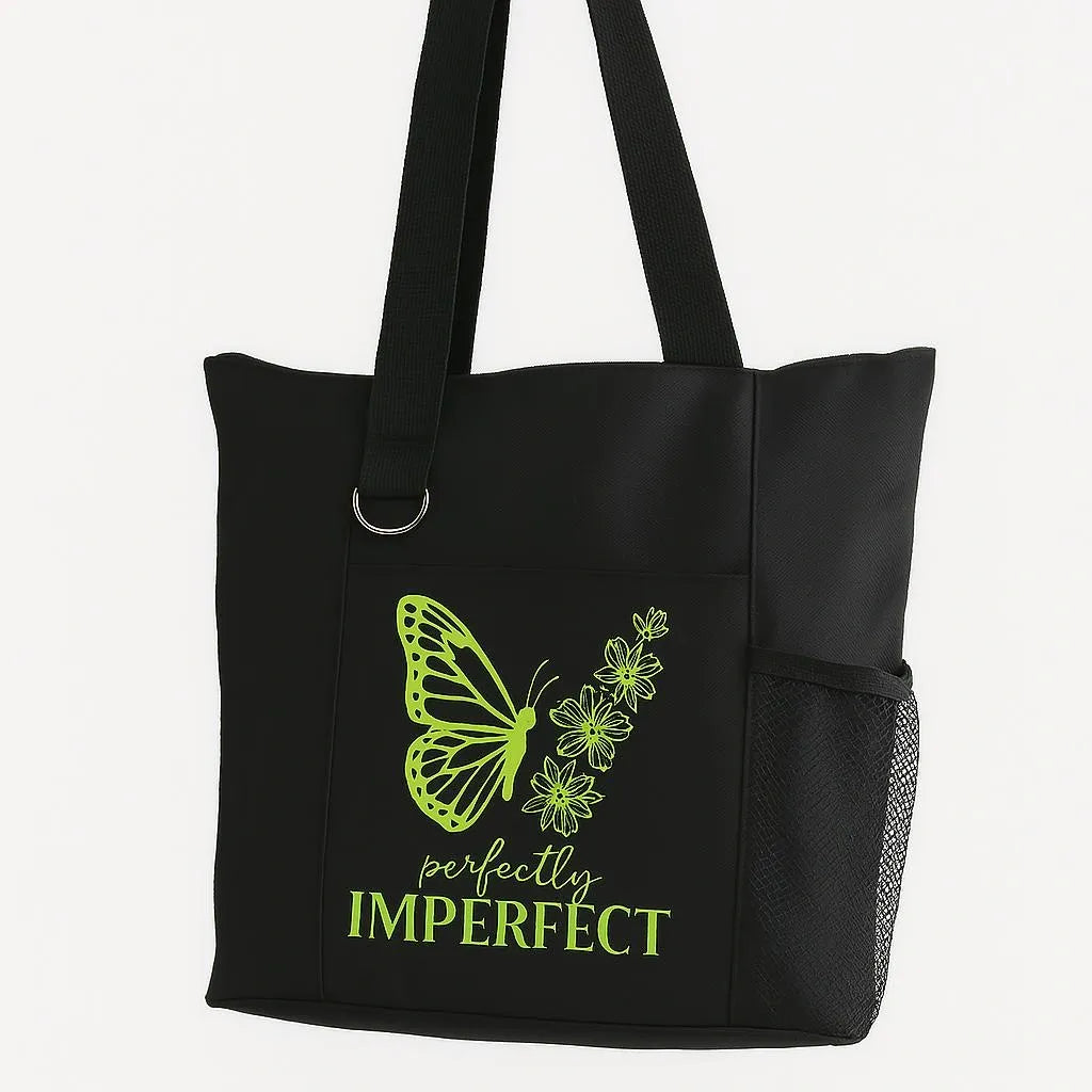 Black reusable tote bag with green butterfly graphic and imperfect inspirational typography design, shoulder tote for shopping, travel, work, school, everyday carry, self love, and motivational lifestyle accessories