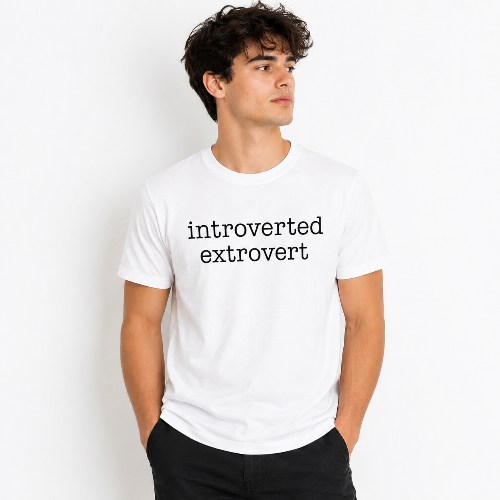 A man wearing a white crewneck t-shirt with the text 'introverted extrovert' printed in black lowercase serif font on the chest, paired with black pants, set against a plain white background.