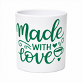 A white ceramic mug with the phrase 'Made with love' printed in green script and serif lettering, accompanied by small heart and coffee cup illustrations, shown on a plain white background.
