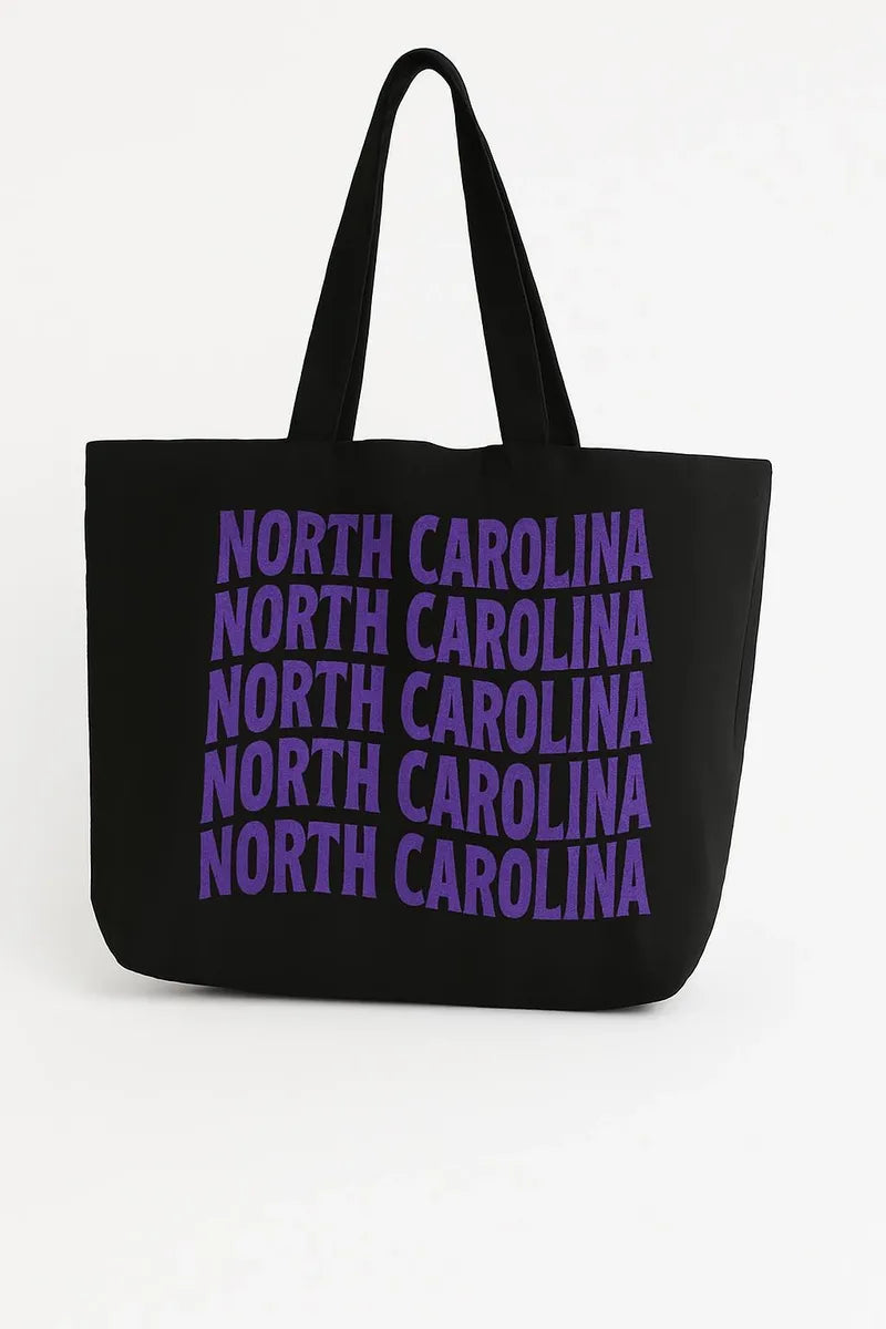 Black cotton tote bag with purple North Carolina typography design, reusable state pride shoulder bag for shopping, travel, school, and casual everyday style.