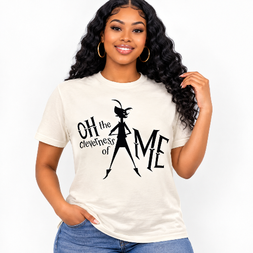 A woman with long, curly black hair wearing a cream-colored graphic t-shirt with a black print of a goat character and the text 'OH the cleverness of AME', paired with blue jeans, against a plain white background.