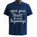 Navy blue graphic t-shirt featuring the inspirational quote "Open Your Heart to New Beginnings" in elegant white script lettering. Motivational unisex shirt perfect for personal growth, encouragement, positivity, everyday wear, gifting, and inspirational fashion.