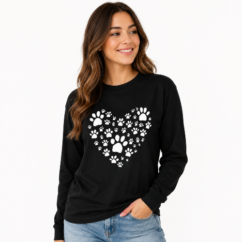 A woman wearing a black long-sleeve crewneck shirt with a white paw-print heart graphic on the chest, paired with blue jeans, against a plain white background.