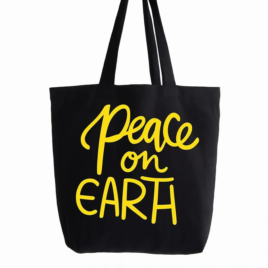 Black cotton tote bag with yellow Peace on Earth typography design, reusable shoulder tote for shopping, travel, school, work, eco friendly lifestyle, everyday carry, and inspirational fashion accessories