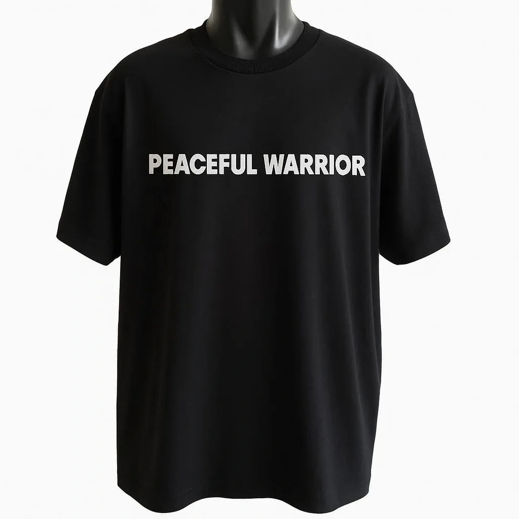 Black graphic t-shirt featuring the phrase "Peaceful Warrior" in clean white typography, inspirational unisex statement tee promoting strength, balance, and confidence.