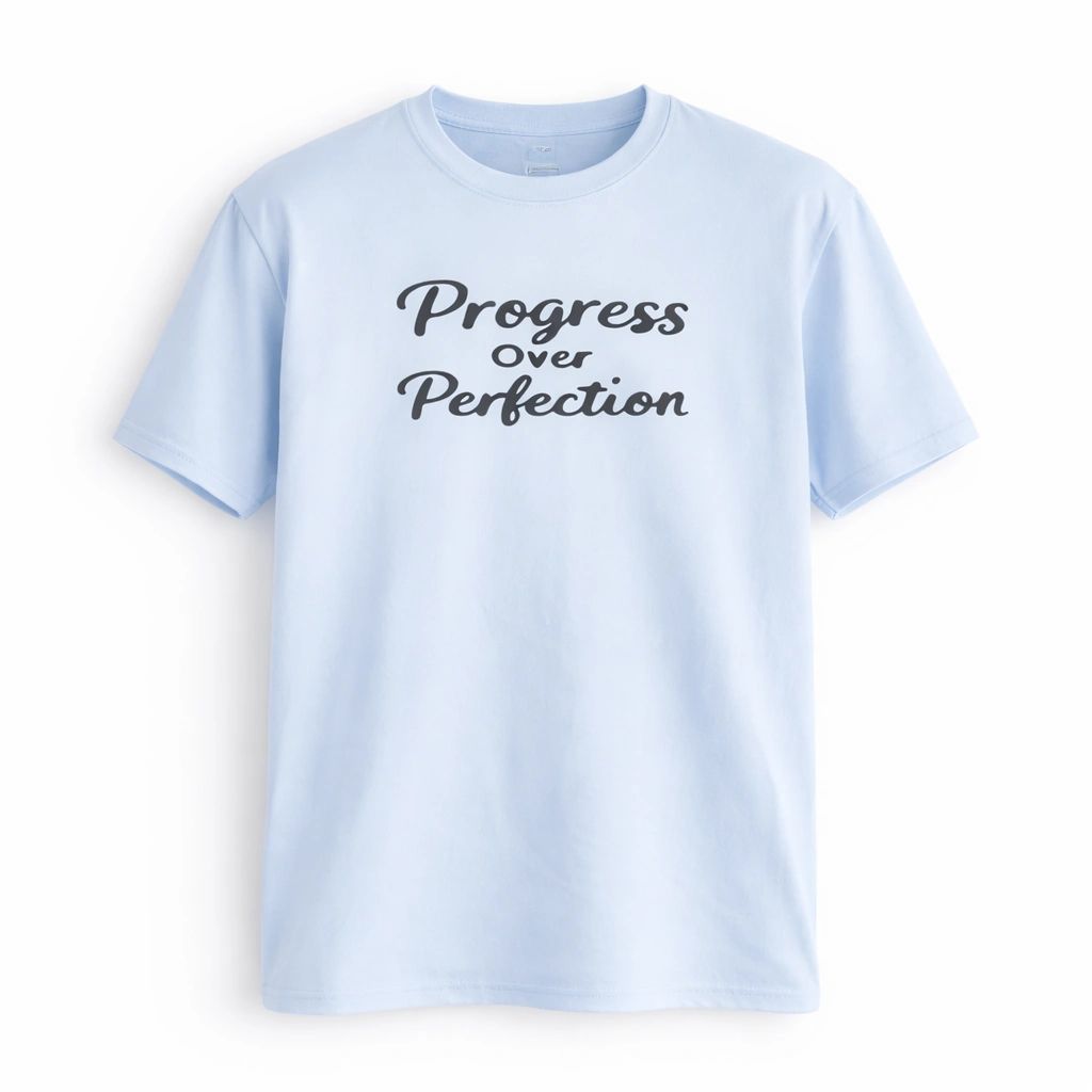 Light blue unisex graphic T-shirt featuring the phrase Progress Over Perfection in elegant script lettering with a minimalist motivational design.
