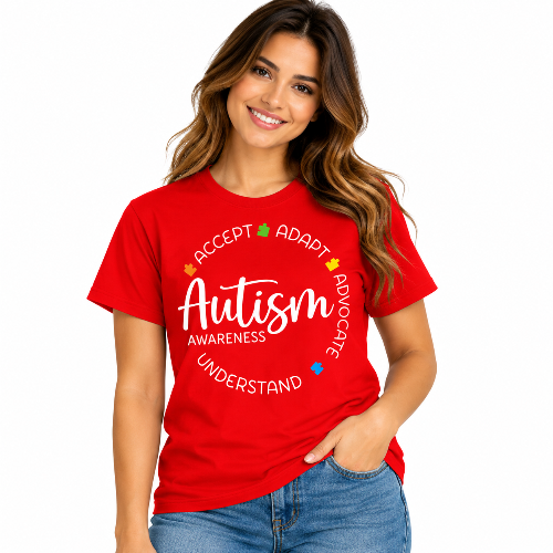 A woman wearing a red short-sleeve graphic T-shirt with a blue puzzle-heart design and the text 'In April We Wear Blue Autism Awareness' on the front, paired with blue jeans against a plain white background.