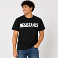 A man wearing a black short-sleeve t-shirt with the word 'RESISTANCE' printed in bold white capital letters across the chest, paired with blue jeans, against a light gray studio background.