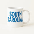 White ceramic coffee mug featuring bold blue South Carolina text design. Perfect gift for South Carolina residents, travelers, tourists, locals, coffee lovers, tea drinkers, and state pride enthusiasts. Great for home, office, birthdays, holidays, and souvenirs.