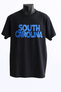 Black graphic t-shirt featuring South Carolina text in bold blue typography, unisex state pride shirt perfect for travel, souvenirs, and everyday wear.