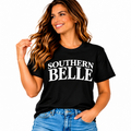 Woman wearing a black Southern Belle graphic T-shirt with bold white lettering and blue jeans.