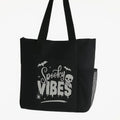 Black tote bag featuring a white Spooky Vibes graphic design on the front. Lightweight reusable shoulder tote with long handles for comfortable carrying. Perfect for Halloween lovers, spooky season fans, shopping, books, work, travel, errands, and everyday use. Stylish gothic-inspired tote bag with a fun spooky aesthetic that stands out against the black background. Ideal for witchy fashion lovers, Halloween enthusiasts, and fans of alternative style.
