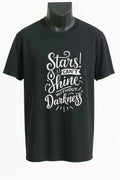 Black graphic t-shirt featuring the inspirational quote "Stars Shine Bright Through Darkness" in elegant white typography. Comfortable unisex motivational shirt for everyday wear, encouragement, hope, and positivity.