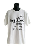 White graphic t-shirt featuring a motivational "Stay Positive" quote design in stylish typography, inspirational unisex graphic tee for everyday wear.