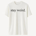 White graphic t-shirt featuring the phrase "Stay Weird" in simple black typography. Minimalist unisex statement shirt designed for self-expression, individuality, creativity, casual fashion, and everyday comfort.