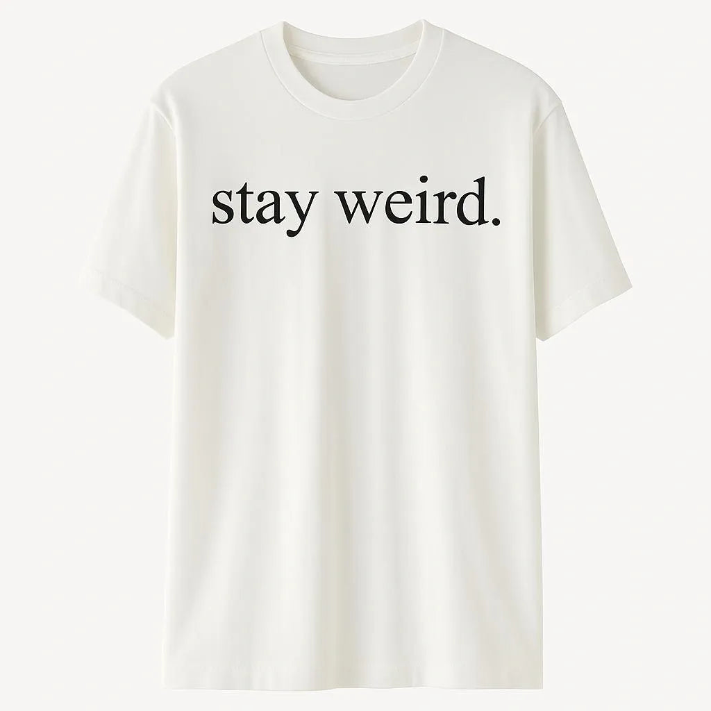 White graphic t-shirt featuring the phrase "Stay Weird" in simple black typography. Minimalist unisex statement shirt designed for self-expression, individuality, creativity, casual fashion, and everyday comfort.