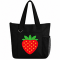 Black reusable tote bag featuring a bright red strawberry with green leaves and yellow seeds, long handles, front pocket, and side mesh pocket.