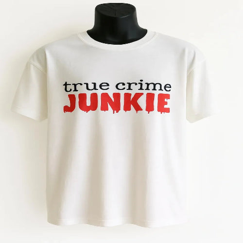 White graphic t-shirt featuring the phrase "True Crime Junkie" in bold black and red lettering. Comfortable casual tee designed for true crime podcast fans, mystery lovers, documentary watchers, and everyday wear. Soft classic fit shirt perfect for lounging, travel, casual outings, and gifting.
