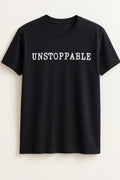 Black graphic t-shirt featuring the word "Unstoppable" in bold white lettering. Motivational statement tee perfect for everyday wear, gym outfits, streetwear fashion, self-confidence, inspiration, and modern casual style.