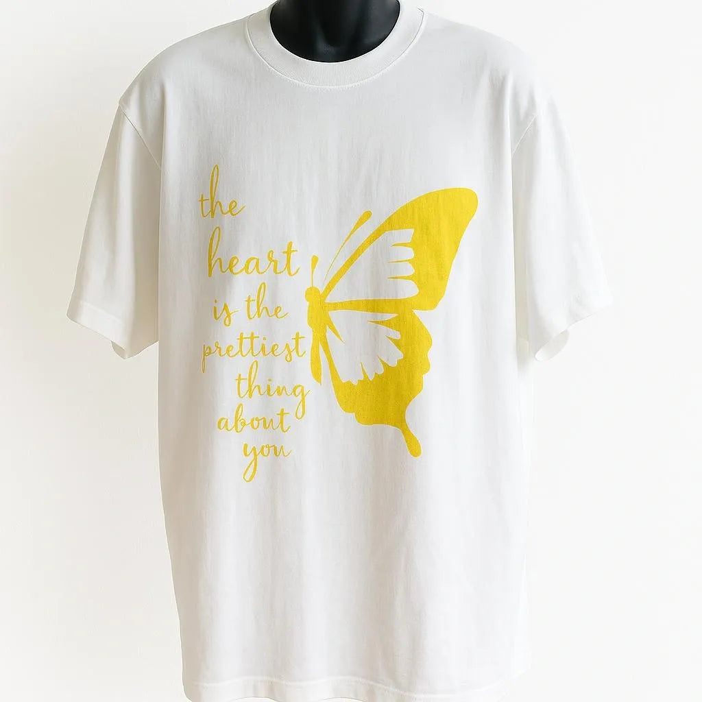 White graphic T-shirt featuring a vibrant yellow butterfly design with inspirational text. Artistic unisex tee inspired by nature, positivity, hope, and personal growth.
